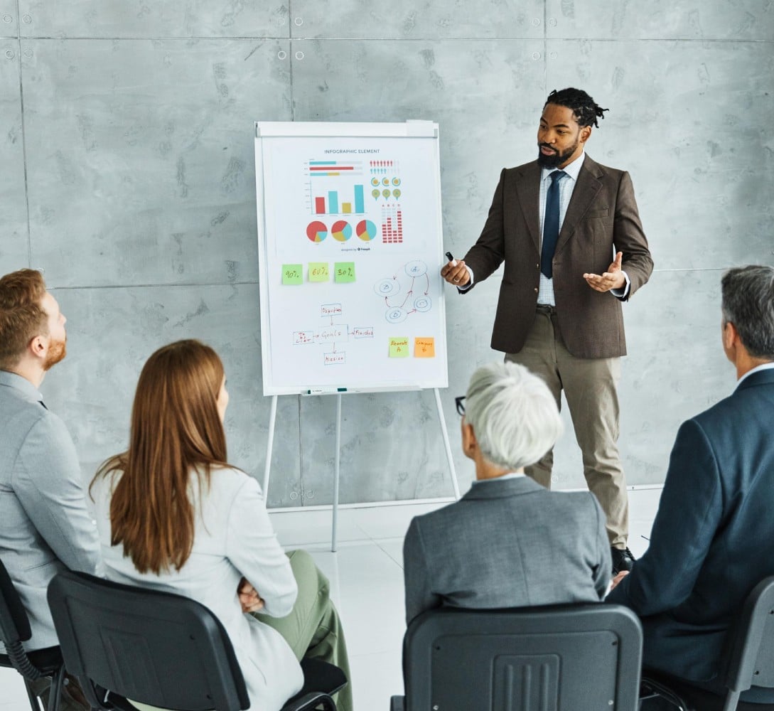 A business professional presenting to a group in a modern office setting.