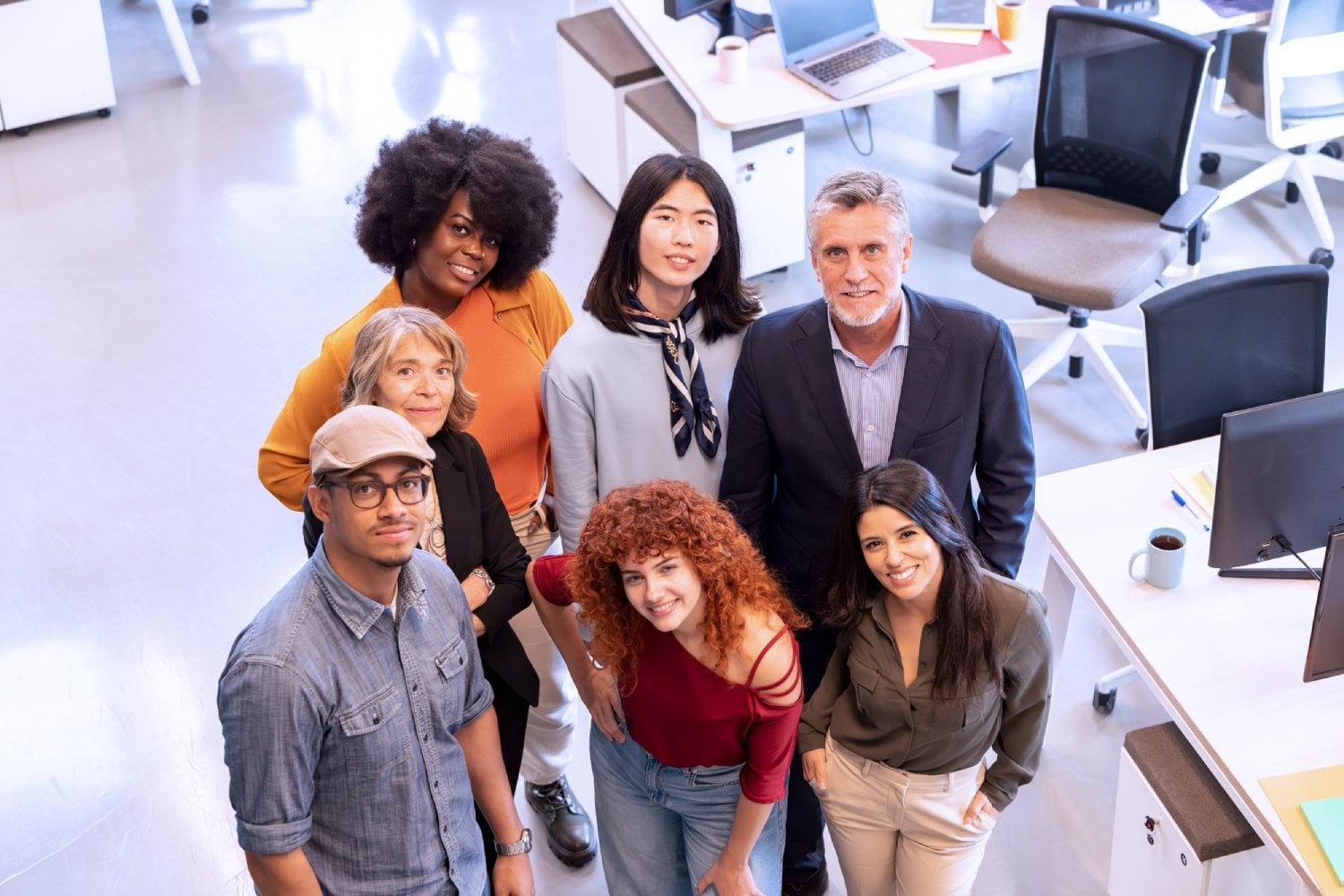 A diverse group of professionals posing together in a modern office environment.