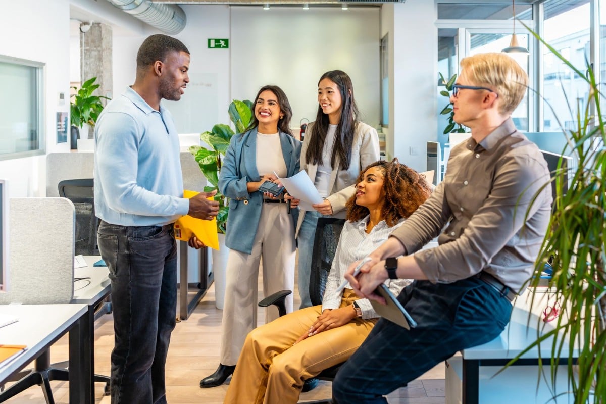 A diverse group of professionals engaged in a discussion in a modern office setting.