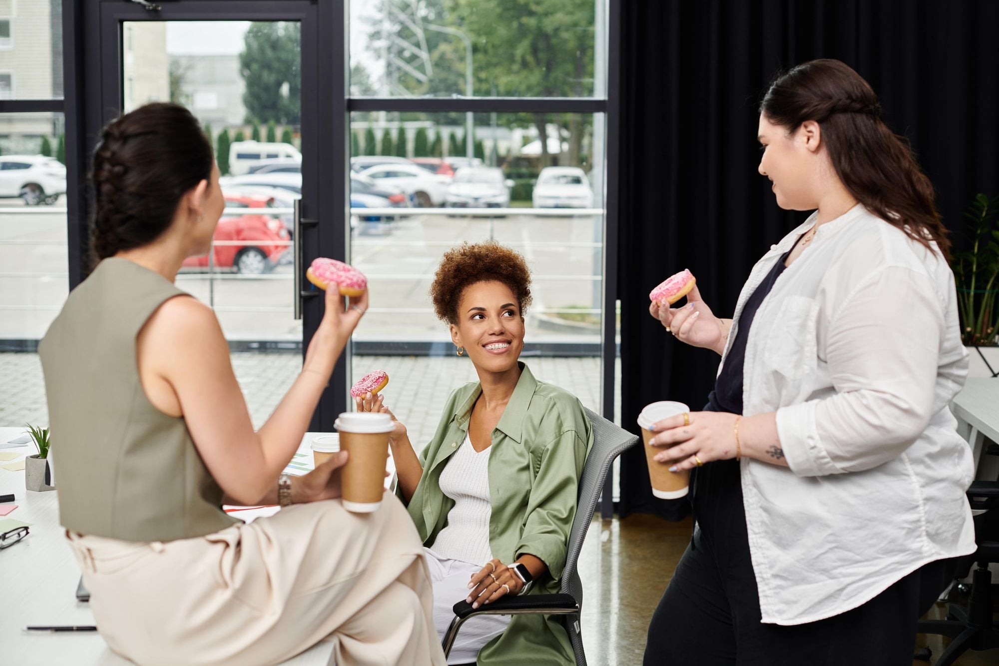 People in a modern office setting enjoying donuts and coffee.
