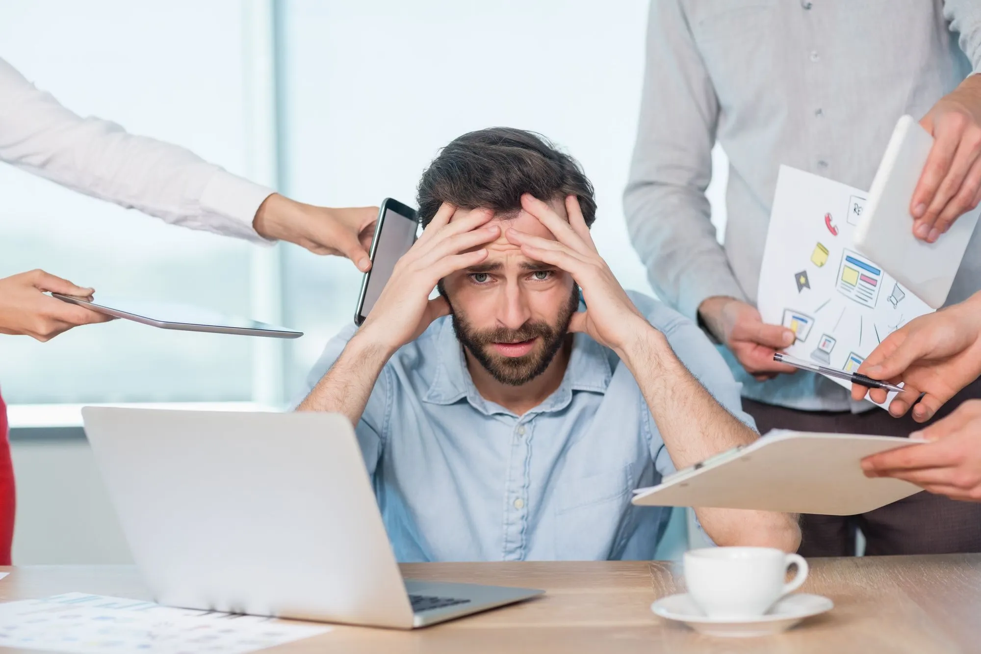 A man at a desk rests his head in his hands, illustrating a moment of contemplation or distress.