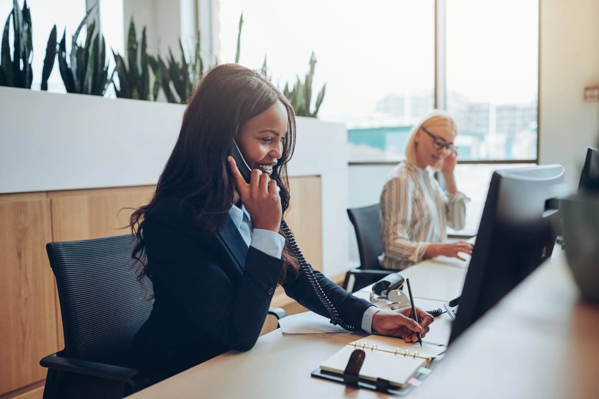 A professional woman wearing a business suit, speaking on the phone with a confident demeanor.