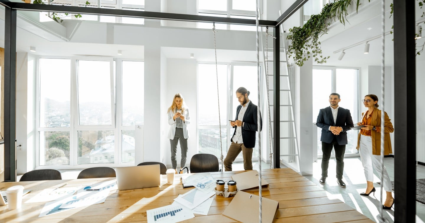 A diverse group of professionals collaborating in a modern office environment, engaged in discussion around a table.
