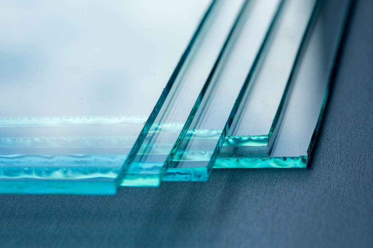Close-up of several glass sheets arranged on a table, showcasing their transparency and reflective surfaces.
