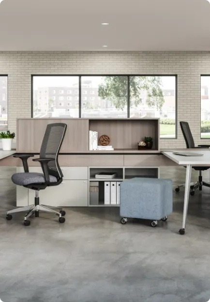 Modern office workstation featuring an ergonomic mesh chair, desk, low storage cabinet, and a light blue rolling ottoman.