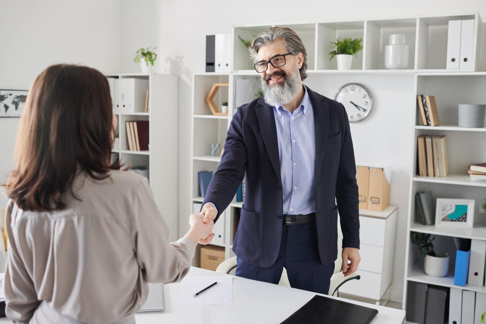A man and a woman shaking hands in a modern office setting.